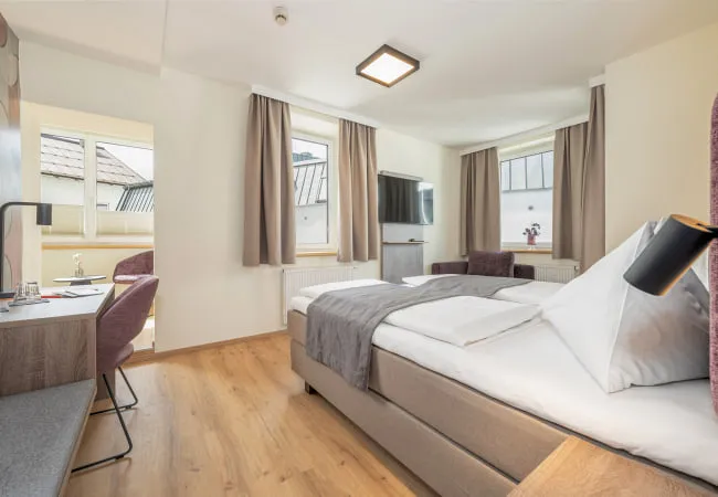 Bright hotel room with two windows and modern furniture