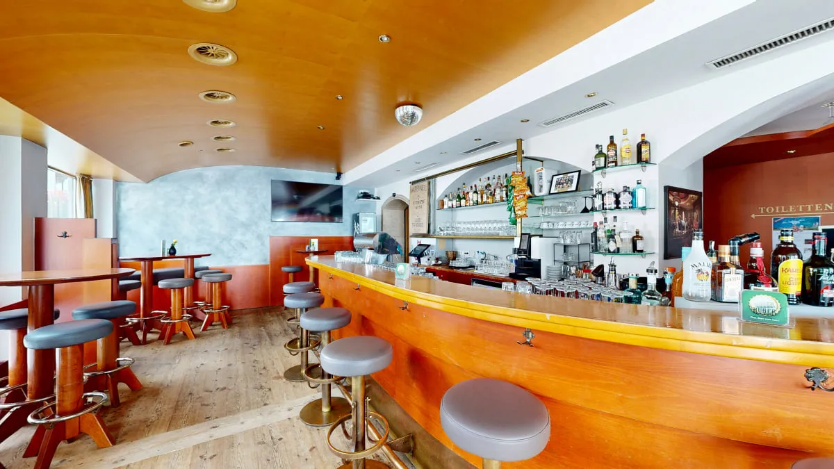 Innenansicht einer Bar mit Hockern und Holztresen