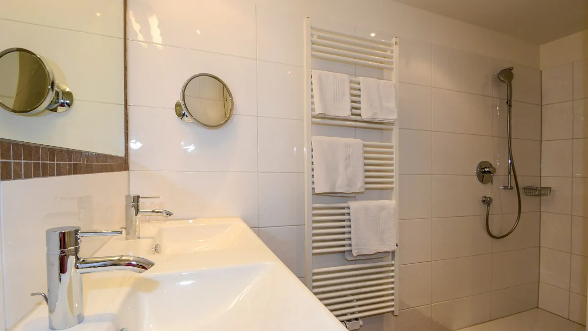 Badezimmer mit Walk-in-Dusche und Doppelwaschbecken im Familienzimmer Kalkstein