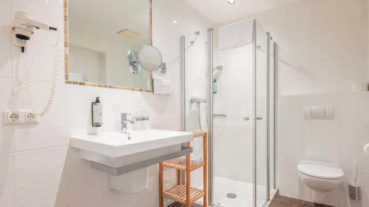 Helles Badezimmer mit Dusche, Waschbecken und Toilette.