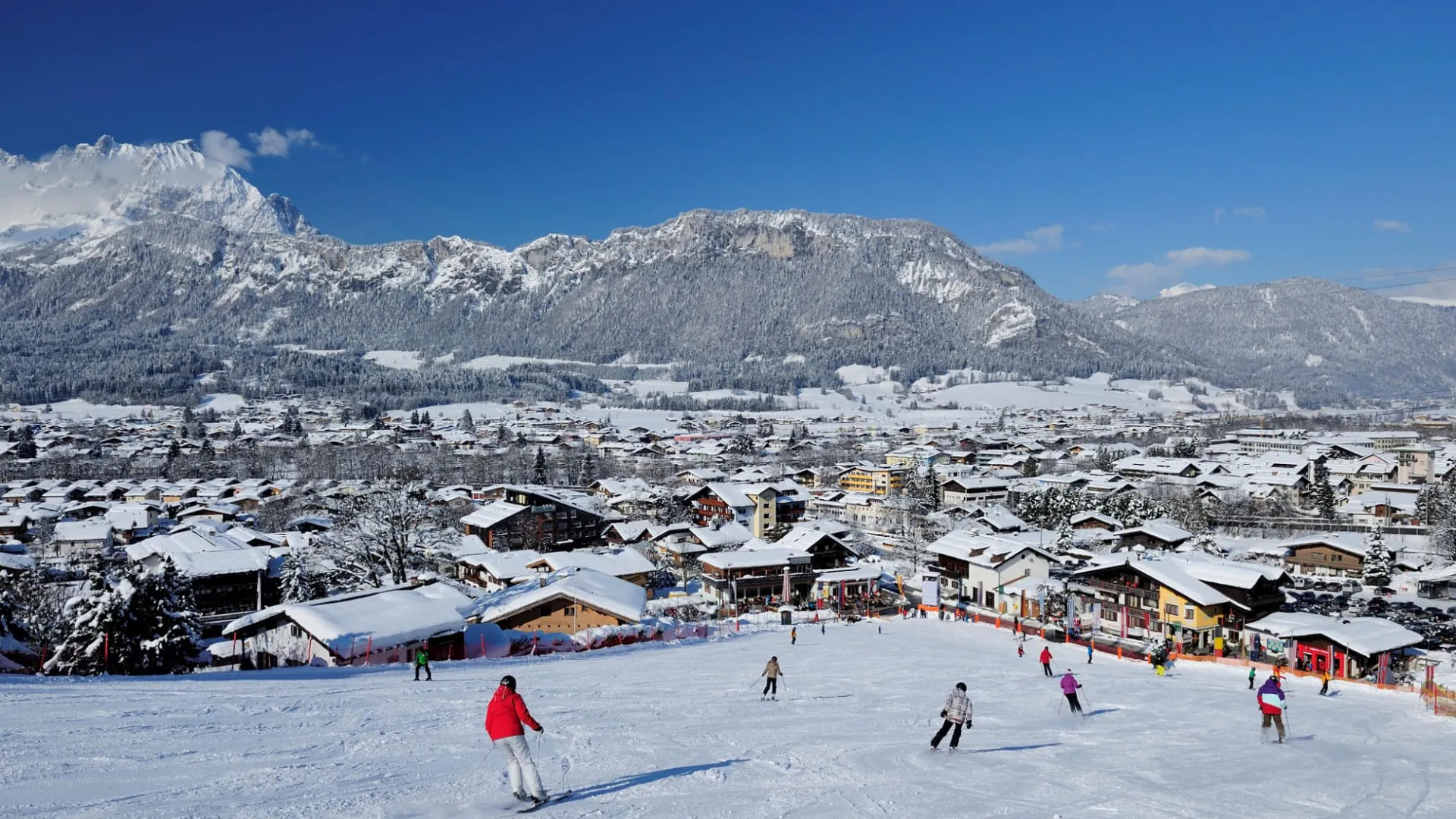 Skifahrer auf der Piste oberhalb von St. Johann in Tirol mit Blick auf den Ort